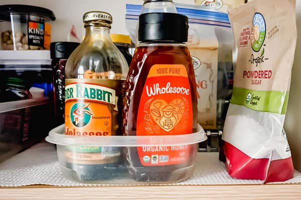 Small plastic container with bottles of honey and molasses.