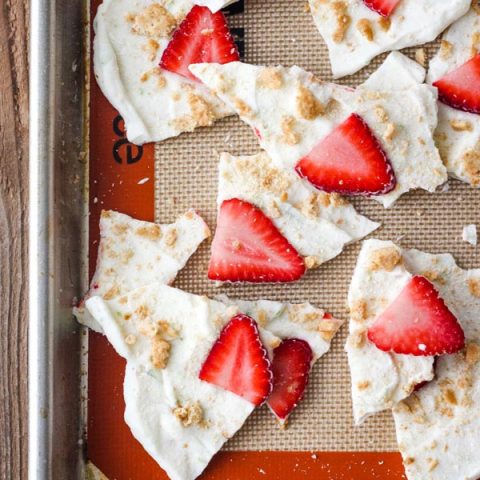 Broken yogurt bark pieces on a silicone mat lined sheet pan.