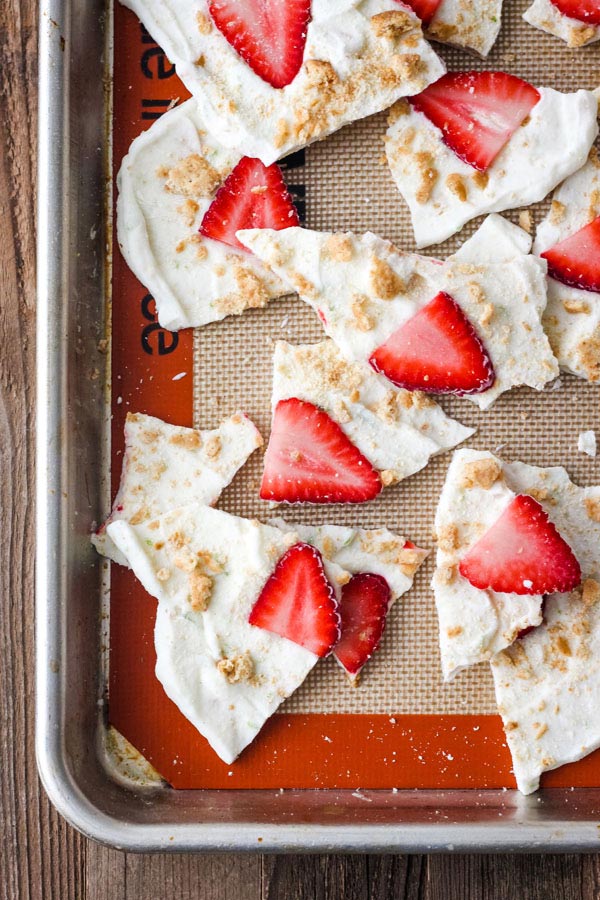 Broken pieces of Strawberry Lime Yogurt Bark on a silicone mat lined sheet pan.