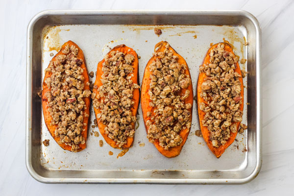 Baked sweet potato halves on a quarter sheet pan.