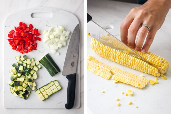 Slicing corn of cob on a cutting board and piles of chopped red pepper, zucchini, and onion.