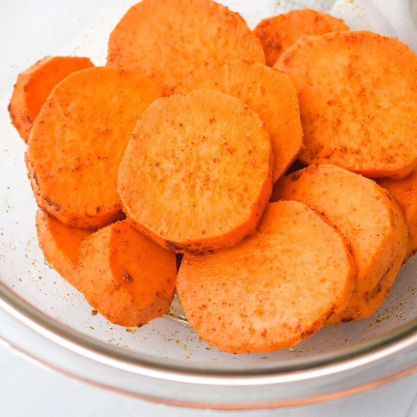 Seasoned sweet potato slices in a bowl.