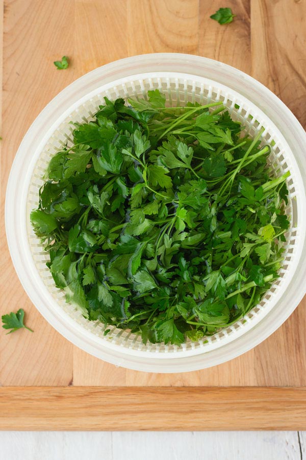 Fresh parsley in a salad spinner filled with water.