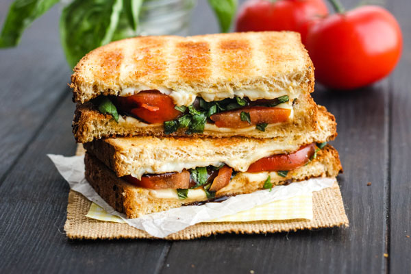 Toasted Caprese Sandwich stacked on a wooden table.