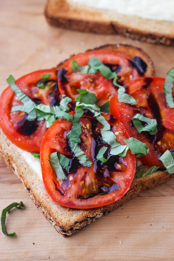 Juicy tomato slices and fresh basil on a piece of cheesy toasted bread.