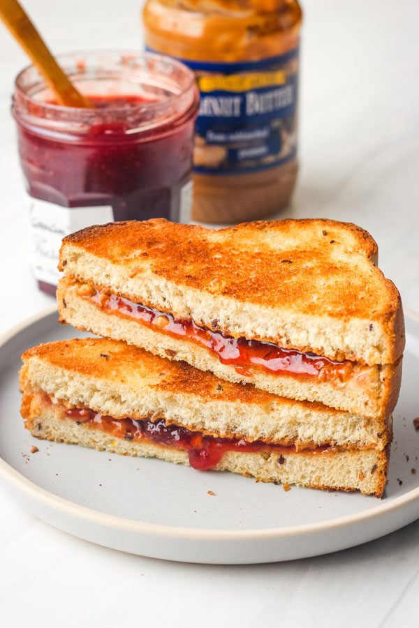 Toasted peanut butter and jelly sandwich slices stacked on a blue plate.