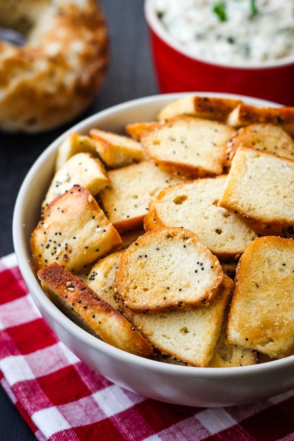 Bagel chips in a bowl on a red checkered napkin.