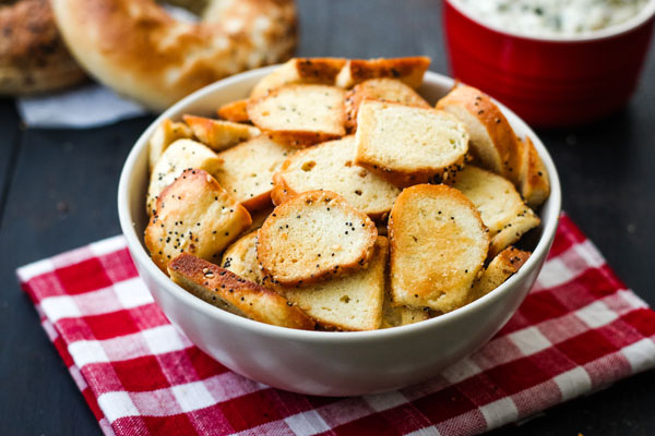 Bagel chips in a bowl on a red checkered napkin.