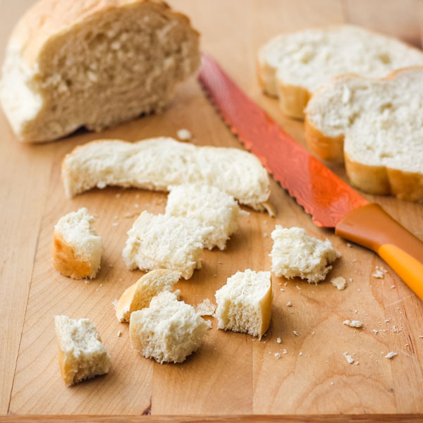 French bread cubed on a cutting board.