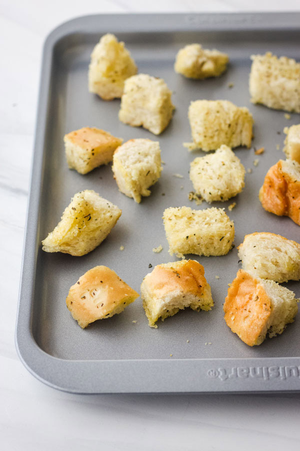 Seasoned bread cubes on a toaster oven baking sheet.