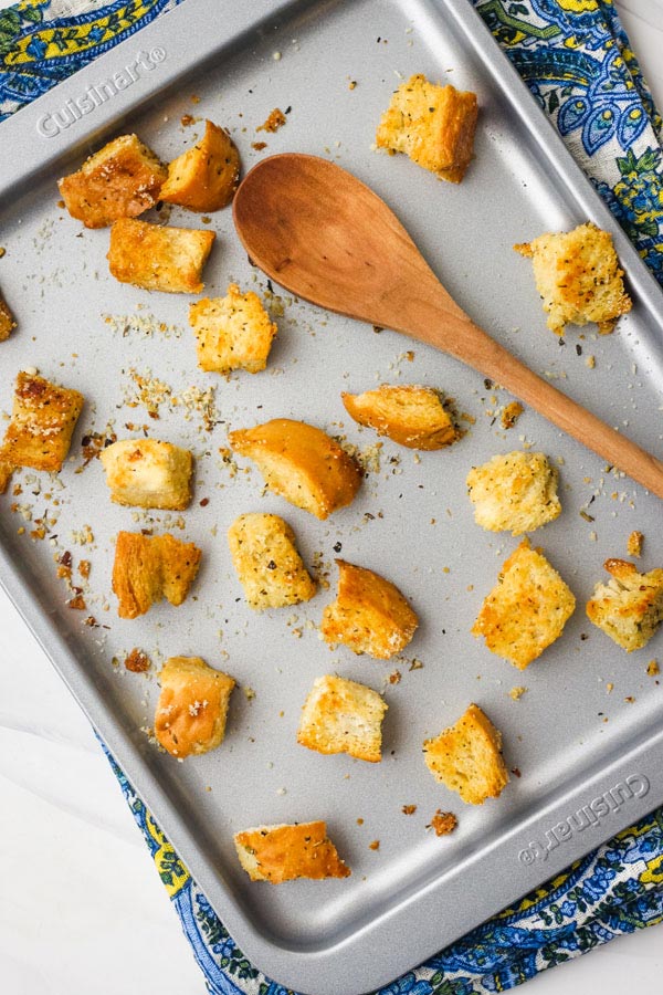 Baked croutons a small baking sheet with a wooden spoon.