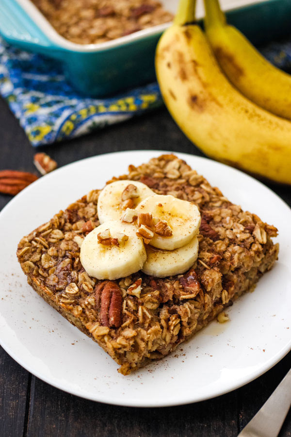 Baked oatmeal square topped with banana slices on a white plate.