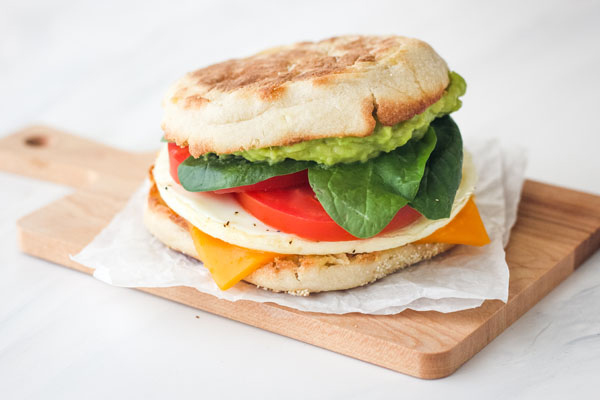 Breakfast sandwich on a small wooden cutting board.