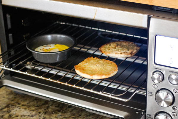 Cooked egg and toasted english muffin halves inside a Breville Smart Oven Pro