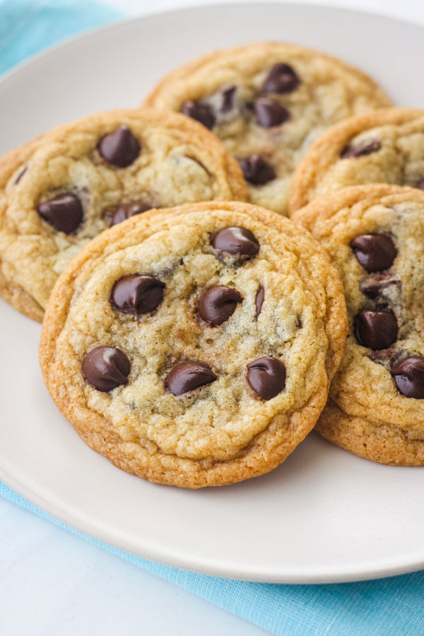 Chocolate chip cookies on a white plate with a light blue napkin.