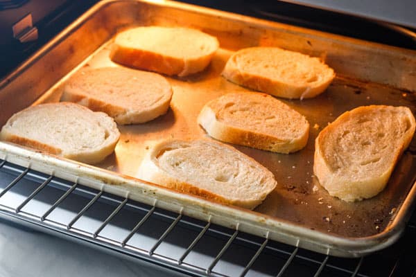 Sheet pan with bread slices inside a toaster oven.