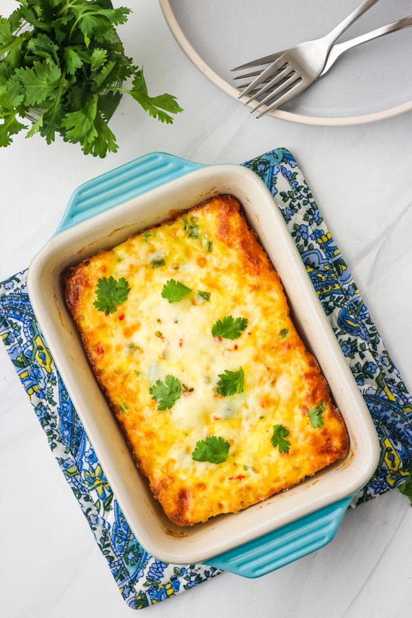 A small egg casserole in a blue baking dish on a white table.