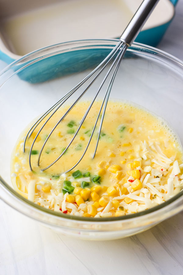 Eggs and ingredients whisked in a glass bowl.