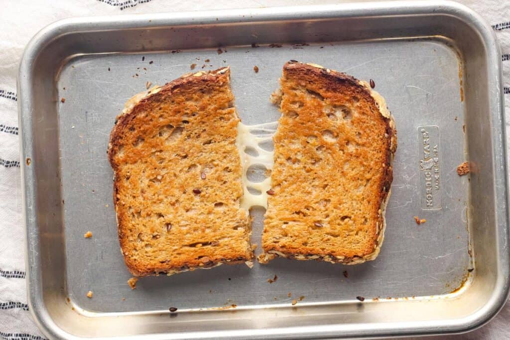 Golden baked grilled cheese split in half on a pan.