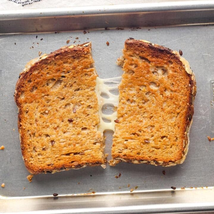 Golden baked grilled cheese split in half on a pan.