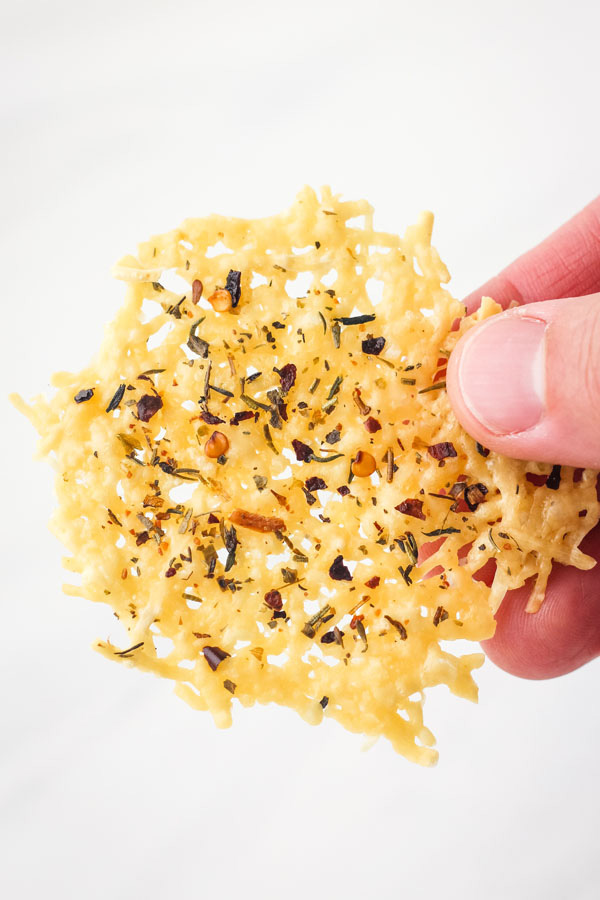 A hand holding a parmesan crisp.