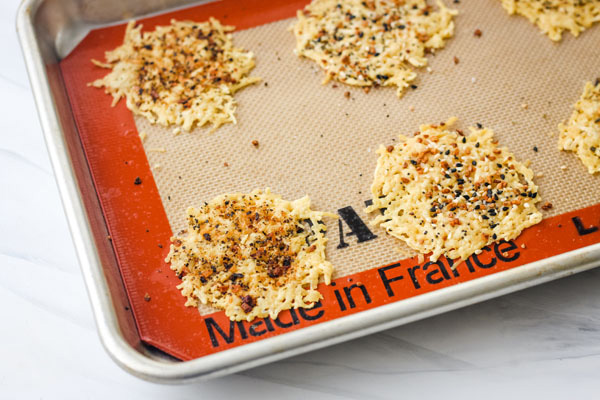 Baked parmesan crisps on a lined sheet pan. 