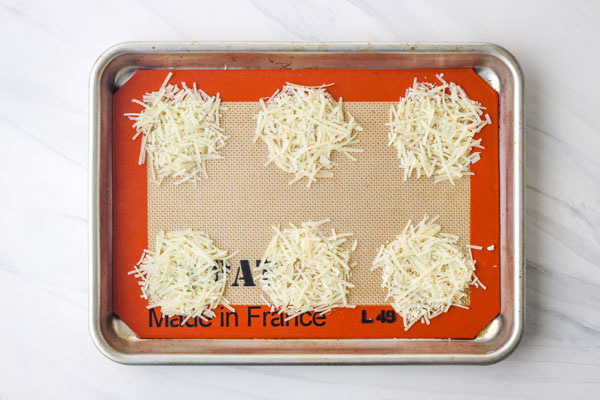 Piles of parmesan cheese on a silpat lined pan.