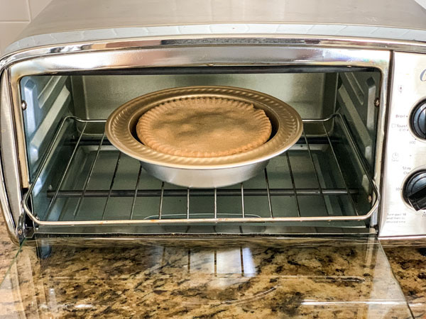 Individual pot pie in a mini pie plate inside a small toaster oven.