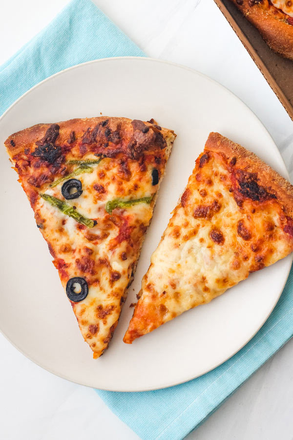 Warm pizza slices on a plate with a blue napkin.