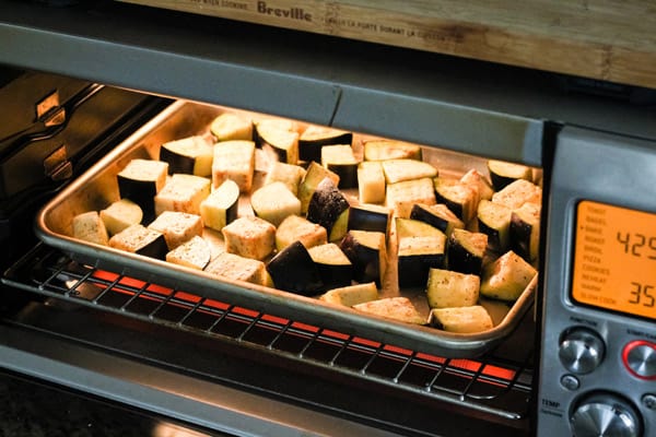 Sheet pan with eggplant cooking in toaster oven.