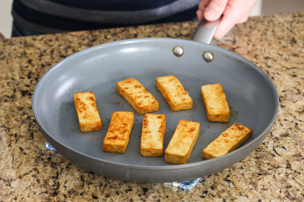 Sriracha baked tofu slices browned in a skillet.