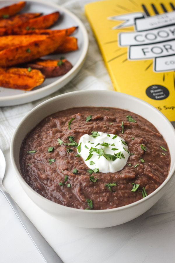 White bowl of black bean soup with a dollop of Greek yogurt.