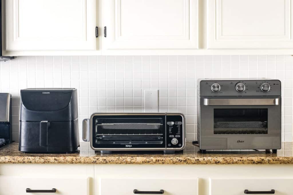 Drawer air fryer and two ovens on a kitchen counter.