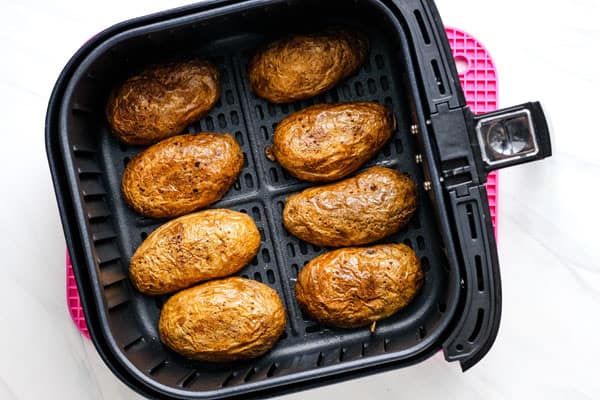 Potato skins crisping in air fryer basket.