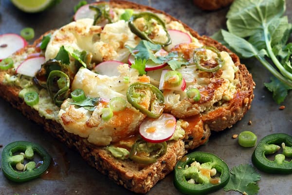 Closeup of prepared avocado toast topped with roasted cauliflower florets.