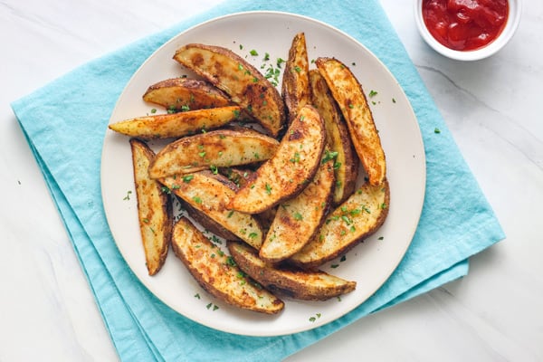 Seasoned potato wedges on plate.