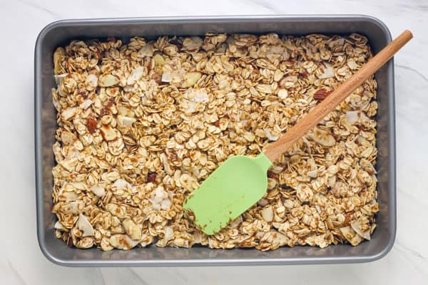Syrup-coated oats in a small metal baking pan.