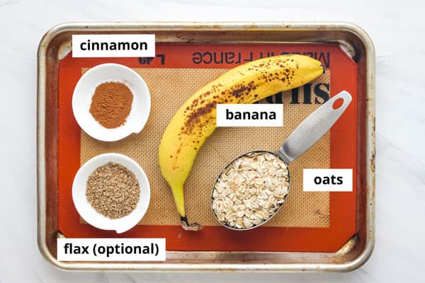 Banana, oats, cinnamon, and flax labeled on a baking sheet.