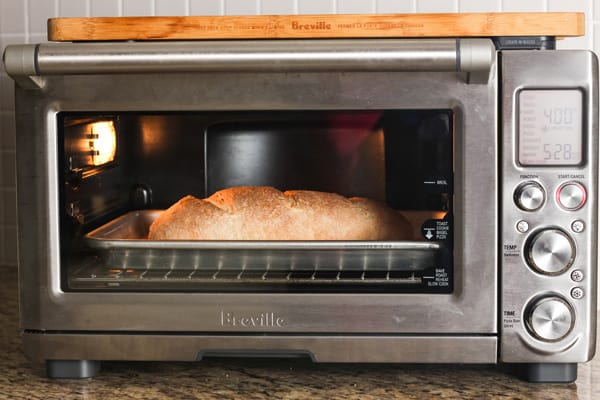 Small loaf of golden brown bread baking in a countertop oven.