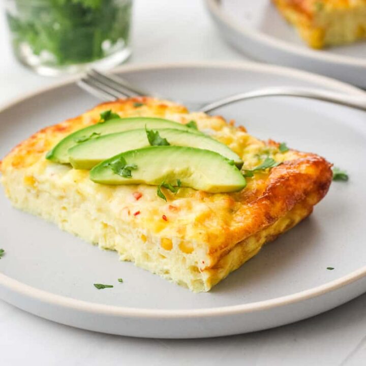 Plate of egg bake topped with avocado slices and cilantro.