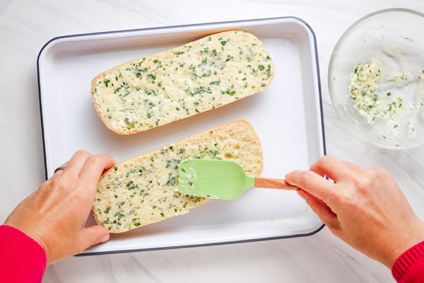 Person spreading butter on bread with a rubber spatula.