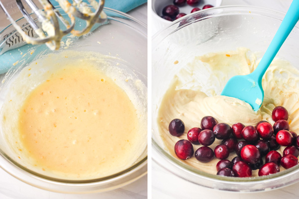 A glass bowl with cake batter, fresh whole cranberries, and a blue rubber spatula.