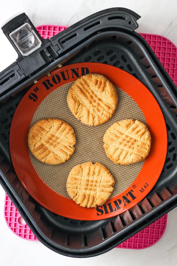 Baked peanut butter cookies inside of an air fryer basket.