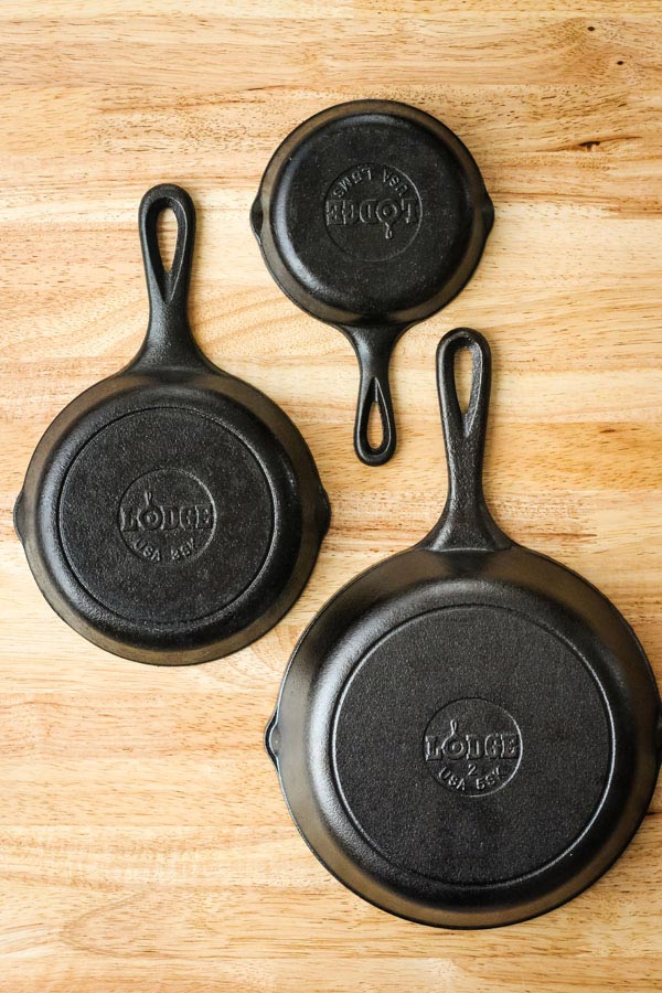 3 cast iron pans on a wood table