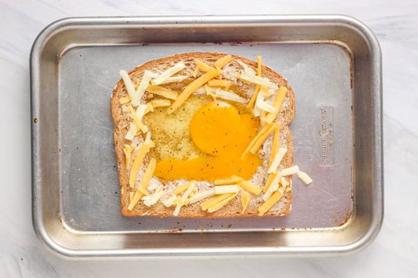 Raw egg and cheese on a piece of buttered bread.