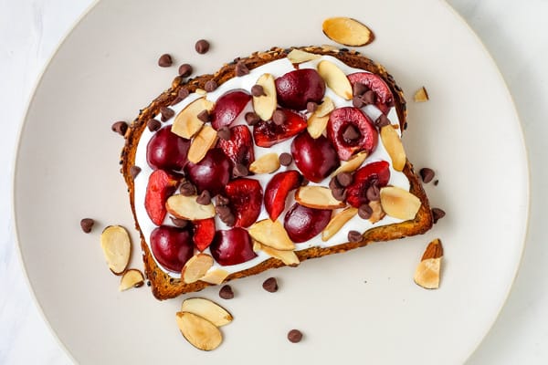 Whole wheat toast topped with whipped cottage cheese and juicy red cherries.