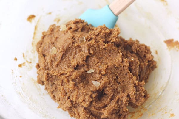 Glass bowl with cookie dough mixed with a rubber spatula.