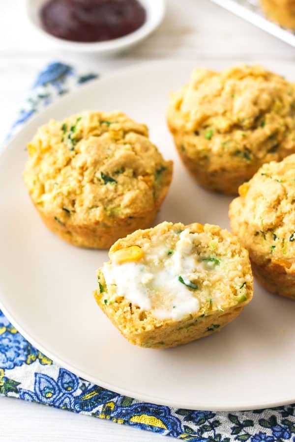 A plate with muffins sliced in half and spread with butter.