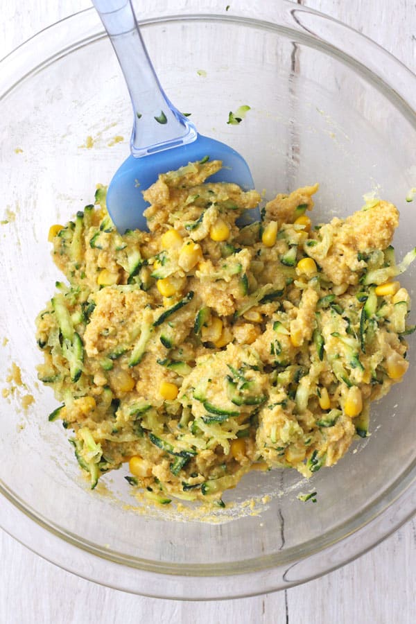 Batter mixed in a glass bowl with a blue rubber spatula.