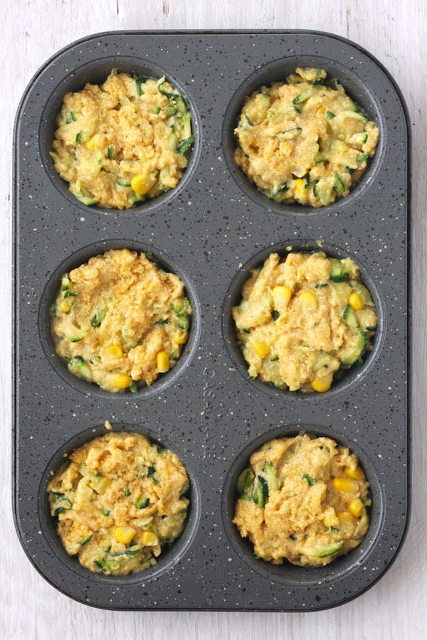 Batter in a gray metal muffin tin.